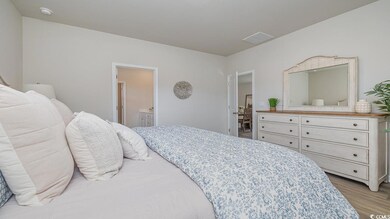 Bedroom with ensuite bathroom and light hardwood /