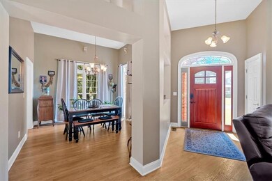 Entryway featuring a chandelier, a towering ceiling, light wood-type flooring, and baseboards