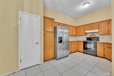 Kitchen with black range with electric stovetop, stainless steel fridge with ice dispenser, a textured ceiling, backsplash, and light tile patterned floors