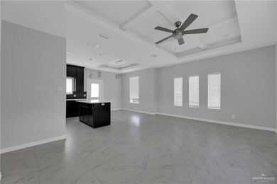 Unfurnished living room featuring ceiling fan, a tray ceiling, and light tile floors