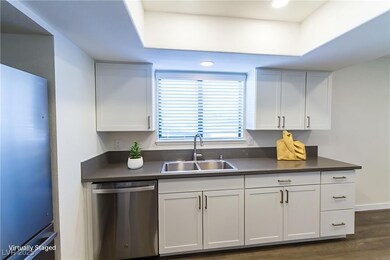 Kitchen with dark countertops, stainless steel dishwasher, freestanding refrigerator, white cabinets, and recessed lighting