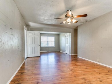 Empty room with baseboards, a ceiling fan, wood fi
