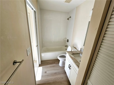 Full bathroom featuring toilet, wood finished floo