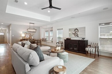 Living room featuring hardwood / wood-style flooring, a raised ceiling, and ceiling fan with notable chandelier