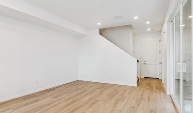 Unfurnished living room featuring light wood finished floors, recessed lighting, and stairs