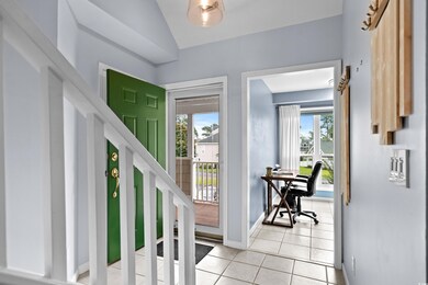 Foyer with light tile patterned floors, baseboards, plenty of natural light, and vaulted ceiling