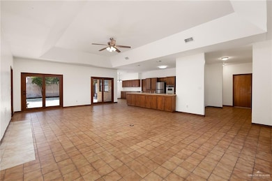 Unfurnished living room with a raised ceiling, ceiling fan, and light tile patterned floors