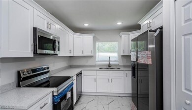 Kitchen featuring stainless steel appliances, white cabinetry, light marble finish floors, light stone counters, and recessed lighting