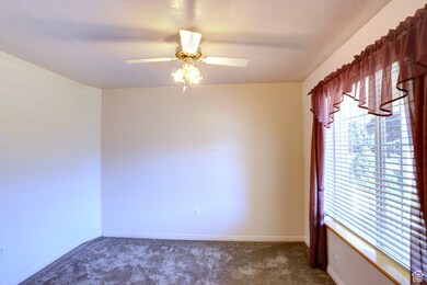 Unfurnished room featuring dark carpet, a ceiling fan, and a textured ceiling