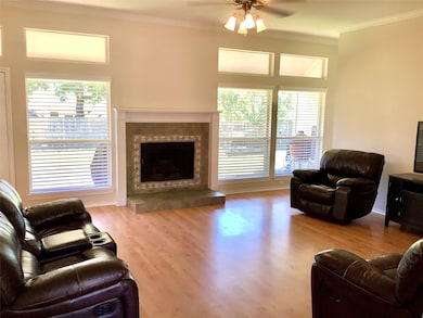 Living area featuring crown molding, light wood-style floors, a premium fireplace, and ceiling fan