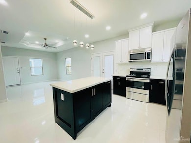 Kitchen with dark cabinets, pendant lighting, light tile patterned flooring, appliances with stainless steel finishes, and white cabinetry