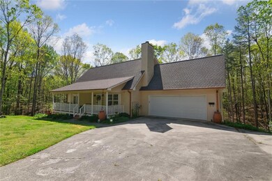 View of front of home featuring a porch, a garage, driveway, a front yard, and a shingled roof