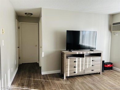 Bedroom with wood finished floors, a textured ceiling, and an AC wall unit