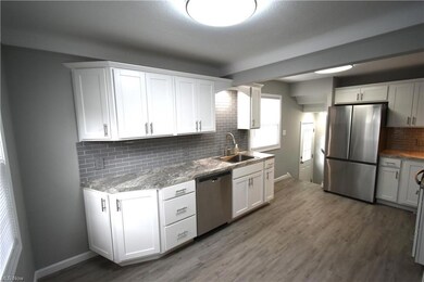 Spacious Kitchen with backsplash, white cabinets, light countertops, appliances with stainless steel finishes, and Vinyl Planking Flooring