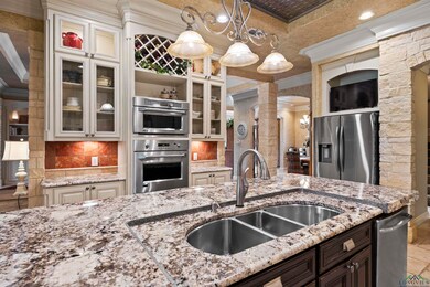 Kitchen featuring ornate columns, crown molding, stainless steel appliances, tasteful backsplash, and light stone countertops