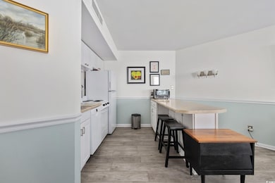 Kitchen with white cabinets, light wood finished floors, and light countertops
