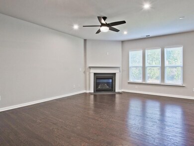 Unfurnished living room featuring ceiling fan, a glass covered fireplace, wood finished floors, and recessed lighting