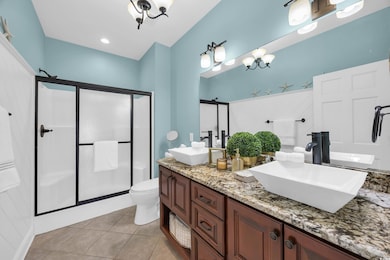 Bathroom featuring a stall shower, double vanity, and light tile patterned floors