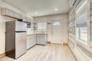 Kitchen with appliances with stainless steel finishes, healthy amount of natural light, an AC wall unit, light countertops, and recessed lighting