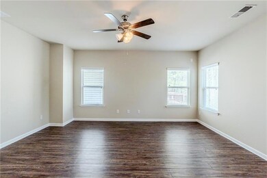 Unfurnished room with dark wood finished floors, baseboards, visible vents, and a ceiling fan