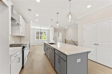 Kitchen featuring gray cabinetry, appliances with stainless steel finishes, crown molding, light countertops, and white cabinets