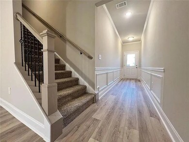 Stairs featuring crown molding, wood finished floors, and a wainscoted wall