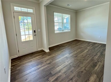 Doorway featuring plenty of natural light, crown molding, and wood finished floors