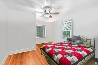 Unit A Bedroom with wood finished floors, multiple windows, a ceiling fan, and a textured ceiling