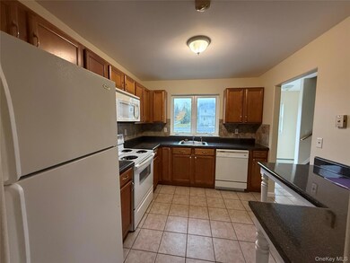 Kitchen with white appliances, brown cabinets, light tile patterned flooring, and backsplash