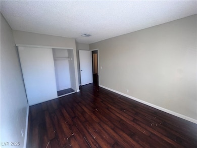 Unfurnished bedroom featuring baseboards, dark woo