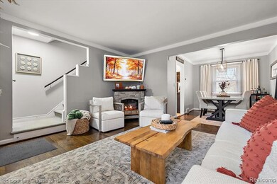 Living area featuring wood finished floors, a fireplace, ornamental molding, and stairway
