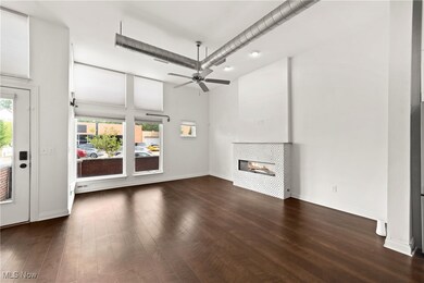 living room featuring a tiled fireplace, dark hardwood / wood-style flooring, a towering ceiling, and ceiling fan