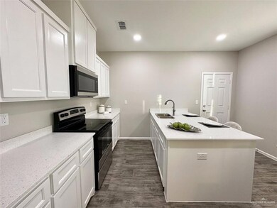 Kitchen with stainless steel appliances, a peninsula, white cabinets, dark wood-style floors, and recessed lighting