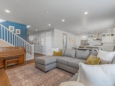 Living room featuring stairway, recessed lighting, hardwood / wood-style floors, a chandelier, and a textured ceiling