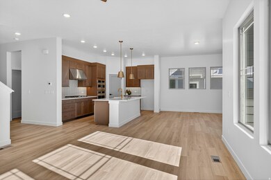 Kitchen with decorative light fixtures, backsplash, a kitchen island with sink, light wood-style flooring, and recessed lighting