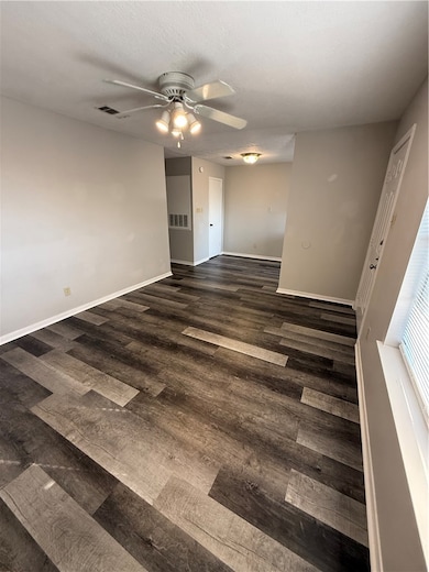 Unfurnished room with dark wood-style floors, ceiling fan, and a textured ceiling
