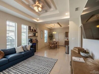 Living area with a tray ceiling, a dry bar, a ceiling fan, light tile patterned floors, and recessed lighting