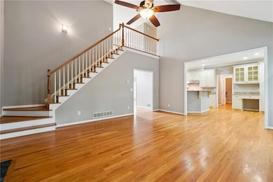 Unfurnished living room with high vaulted ceiling, ceiling fan, and light hardwood / wood-style flooring