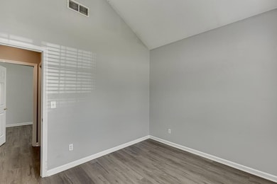 Unfurnished room with vaulted ceiling and wood finished floors