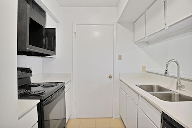 Kitchen with sink, black appliances, a textured ce