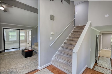 Stairway with ornamental molding, ceiling fan, baseboards, wood finished floors, and lofted ceiling