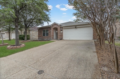 View of front of home featuring concrete driveway, brick siding, an attached garage, a front lawn, and a shingled roof