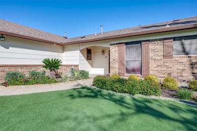 Entrance to property with a lawn, brick siding, and a shingled roof