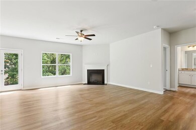 Unfurnished living room featuring a fireplace with flush hearth, plenty of natural light, a ceiling fan, and light wood finished floors