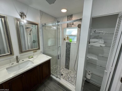 Bathroom featuring tile flooring, vanity, and a shower with door