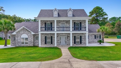 View of front of house with a shingled roof, covered porch, a front yard, and brick siding