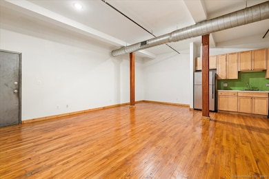 Open floor plan living room, dining room and kitchen with 10+ foot ceilings, exposed wood beams and ductwork