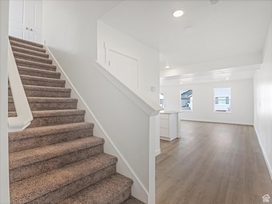 Stairs featuring recessed lighting and wood finished floors