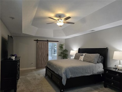 Bedroom with a tray ceiling, light carpet, a barn 