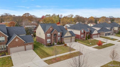 View of front facade with a residential view, concrete driveway, an attached garage, and brick siding